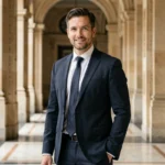 Portrait élégant d'un homme en costume sombre dans un hall parisien, évoquant l'atmosphère politique et mondaine d'un mariage médiatisé